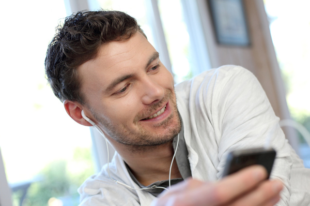 Young man using mobile phone with handsfree headset